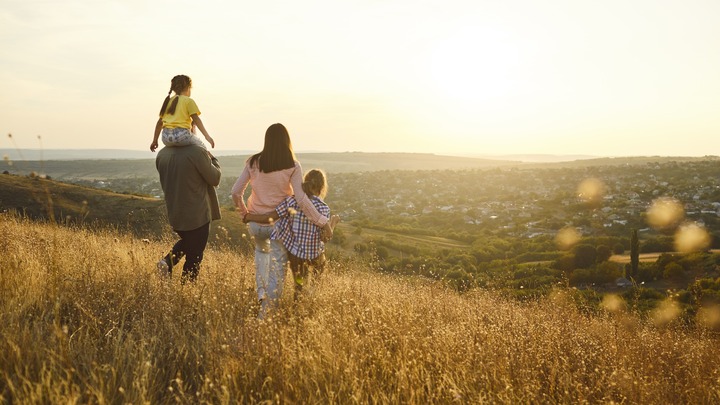 Familie mit zwei Kindern läuft auf Wiese entlang